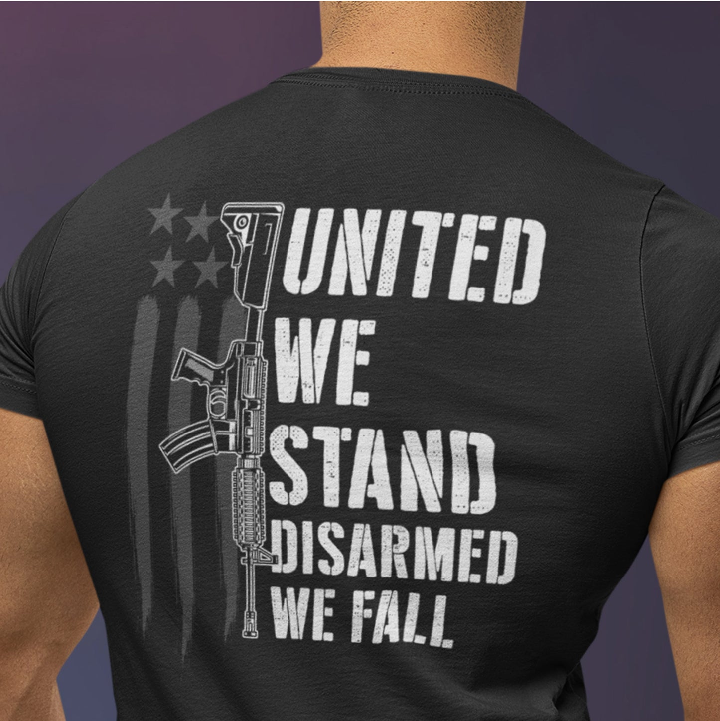 Close up back view of man in Disarmed We Fall 2nd amendment t-shirt showing white rifle graphic with text ‘United We Stand, Disarmed We Fall’ over distressed American flag background.