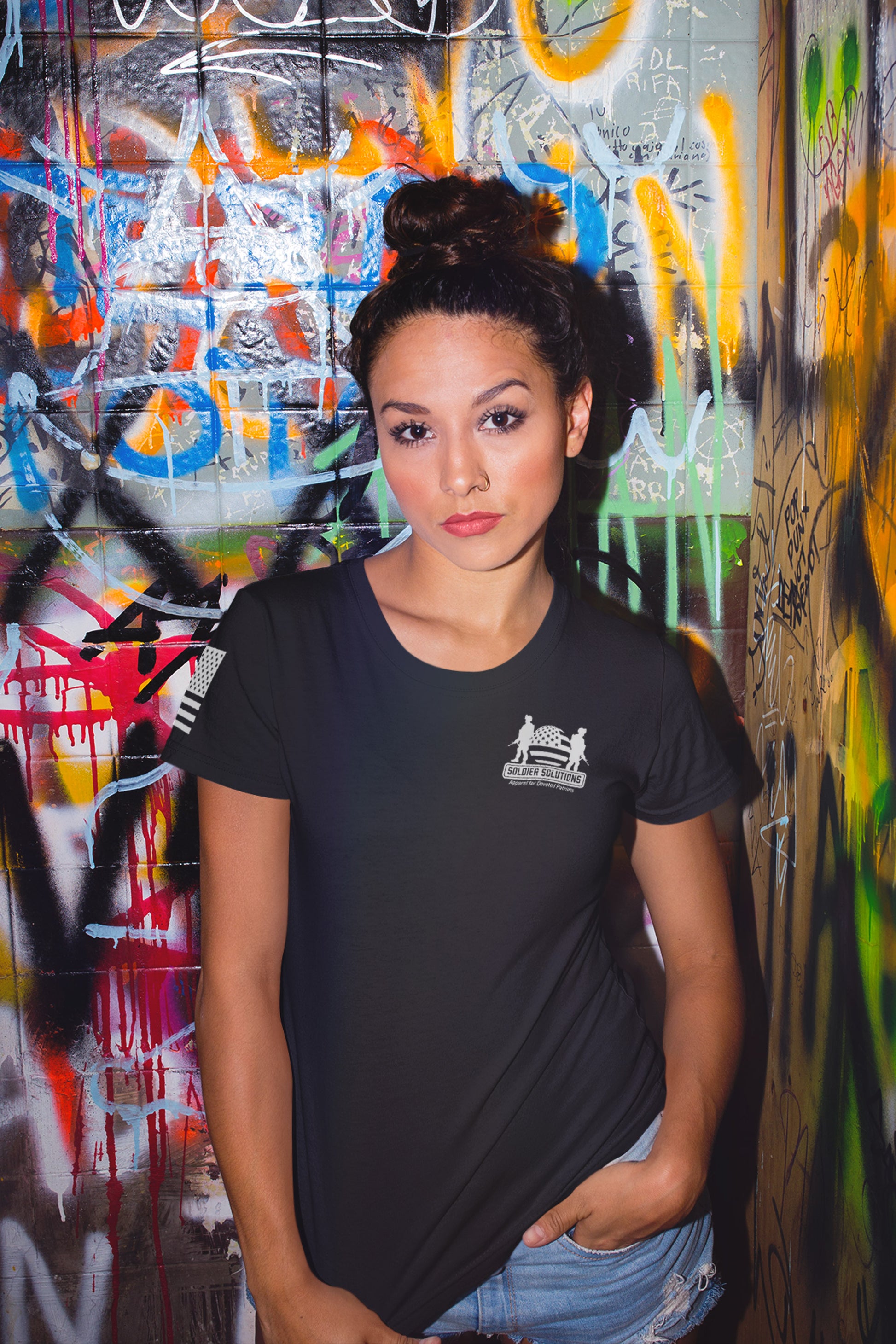 Woman wearing United We Stand Disarmed We Fall women’s 2nd amendment t-shirt with front Soldier Solutions logo and sleeve flag print, standing confidently.