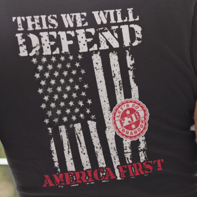 Close-up of distressed American flag graphic with "This We Will Defend America First" text on women's t-shirt