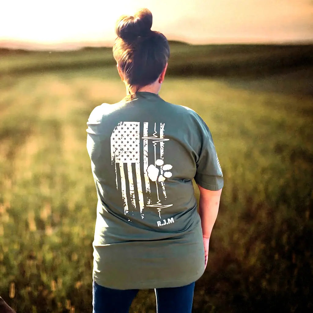 Tribute t-shirt back graphic with American flag, heartbeat line, and initials representing a veteran lost to suicide.