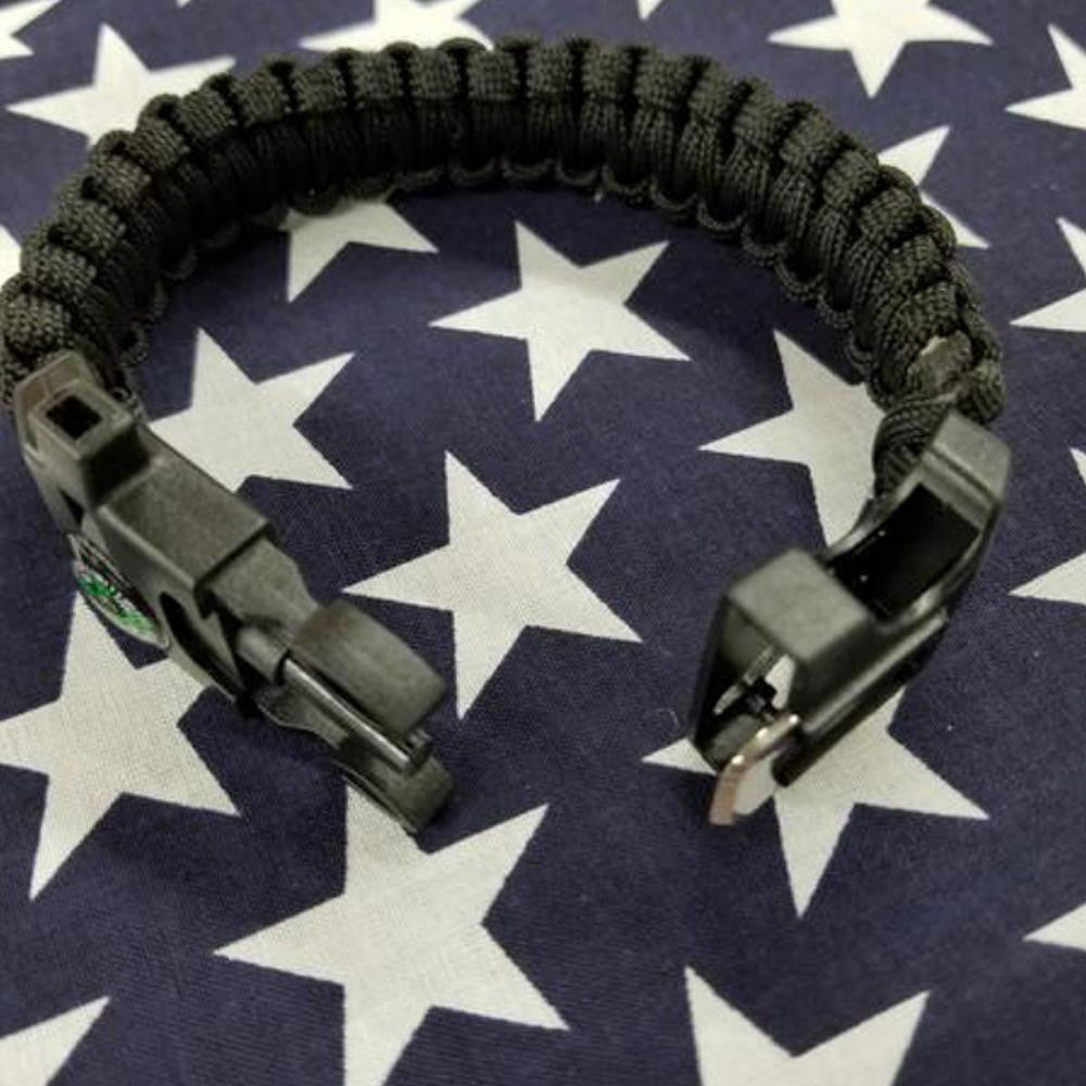 Black paracord survival bracelet with flint fire starter and tactical buckle open.
