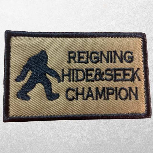 Tactical tan Reigning Hide and Seek Champion morale patch with black embroidered Bigfoot and text