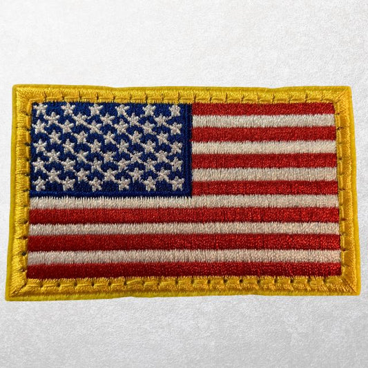 Full-color American flag morale patch with yellow border and tactical hook backing