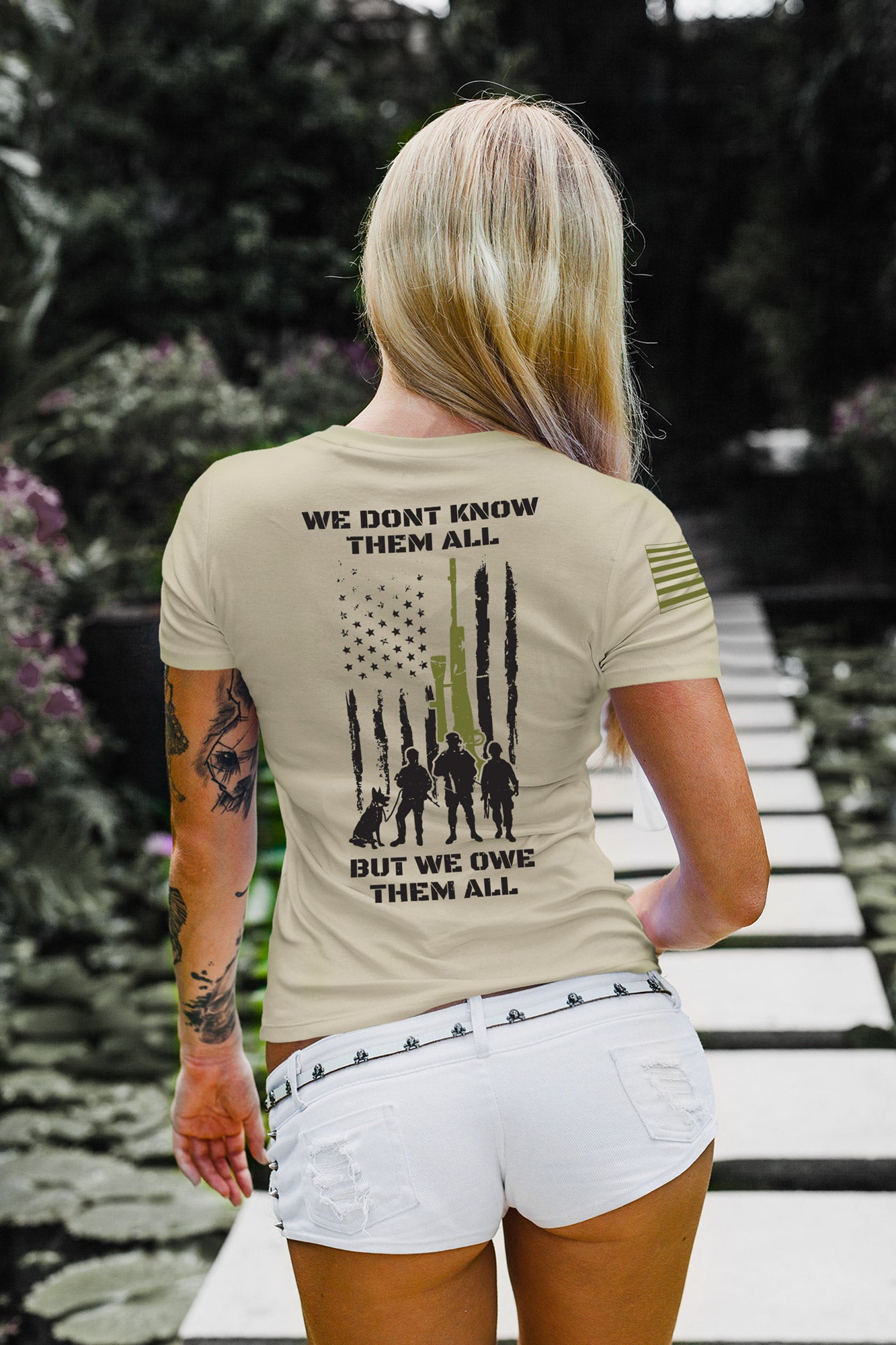 Full back view of women’s military tribute shirt with American flag, rifle graphic, and silhouettes honoring fallen soldiers.