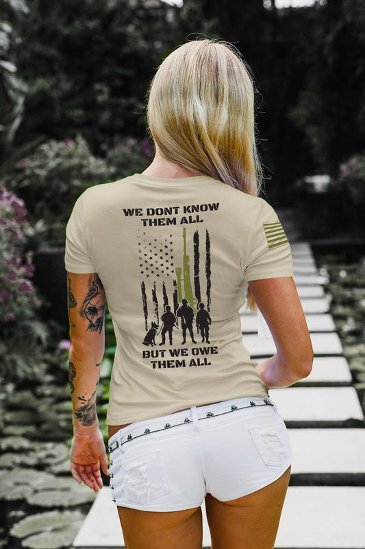 Full back view of women’s military tribute shirt with American flag, rifle graphic, and silhouettes honoring fallen soldiers.