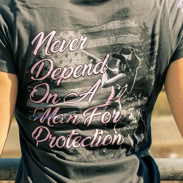 Close-up of pink quote and rifle silhouette with American flag on women’s back graphic tee