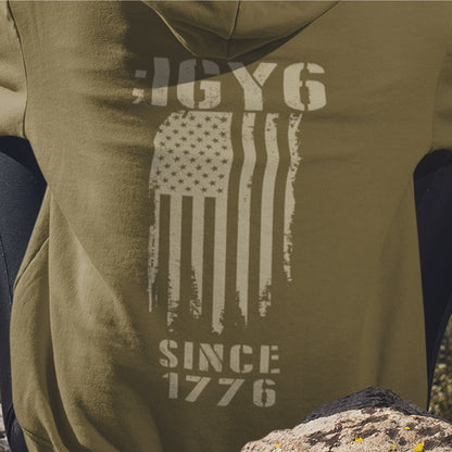 Close up of IGY6 Since 1776 women’s hoodie featuring distressed American flag and bold patriotic back print with sleeve insignia.