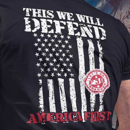 Closeup of “This We Will Defend” back print with faded American flag and America First message on men's shirt