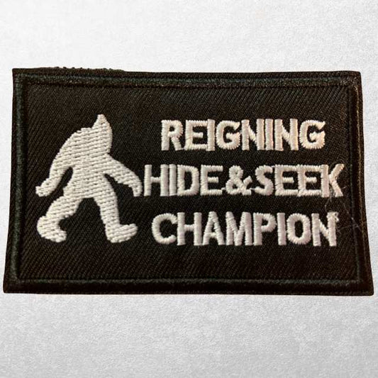 Black Reigning Hide and Seek Champion MOLLE patch with white embroidery featuring Bigfoot