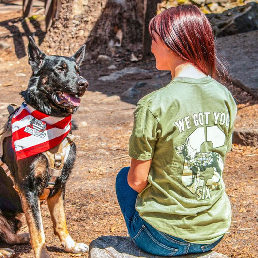 Woman wearing We Got Your Six shirt seated near service dog in patriotic bandana