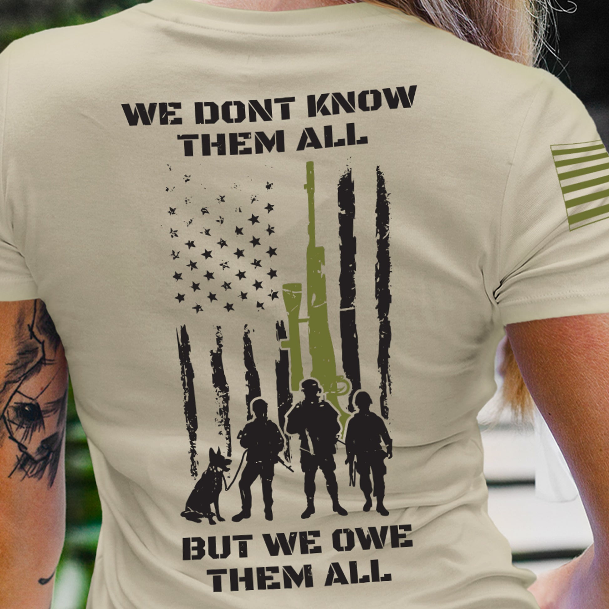 Close-up of women’s tribute shirt with distressed flag, soldiers, and ‘We Don’t Know Them All, But We Owe Them All’ message.
